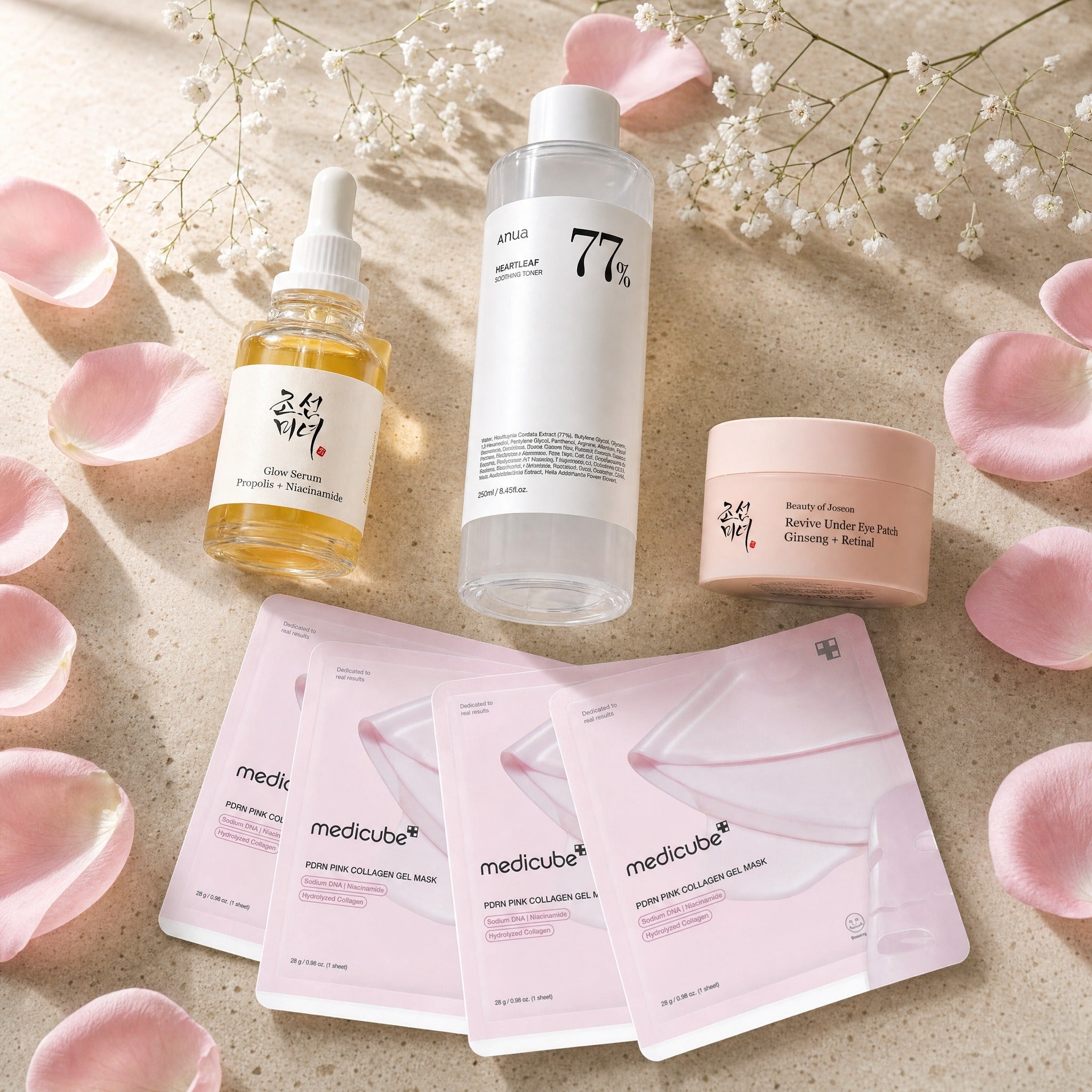 The New-Mum Glow Rescue — Beauty of Joseon Glow Serum, Anua Heartleaf 77% toner, BoJ Revive under-eye patch jar and four square Medicube PDRN pink collagen gel masks on travertine